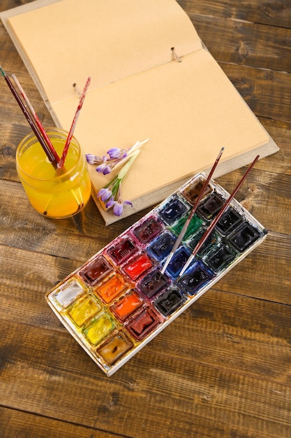 Photo composition avec pinceaux aquarelles colorées et sketcher sur fond de bois