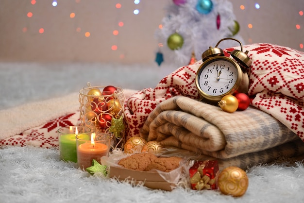 Composition avec plaids, bougies et décorations de Noël, sur tapis blanc sur fond clair