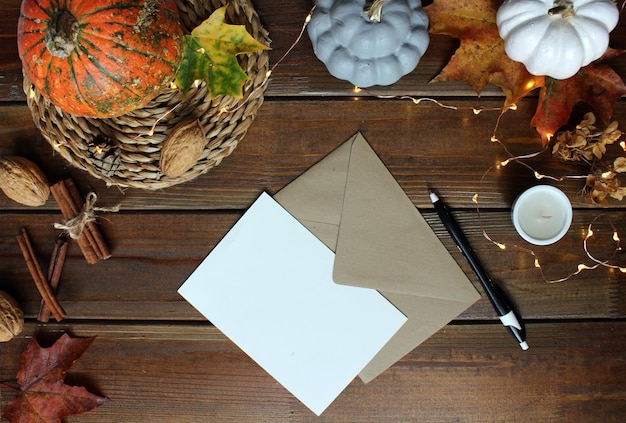 Composition à plat d'automne avec papier vierge carte lettre enveloppe tasse à café écharpe feuilles tombées sur fond beige Automne style hygge table de bureau vue de dessus