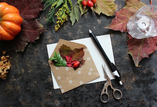 Composition à plat d'automne avec papier vierge carte lettre enveloppe tasse à café écharpe feuilles tombées sur fond beige Automne style hygge table de bureau vue de dessus