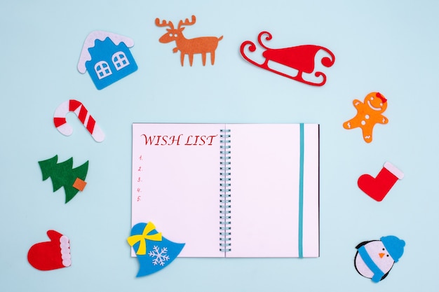 Composition à plat avec cahier ouvert vierge avec lettrage WISH LIST et décorations de Noël