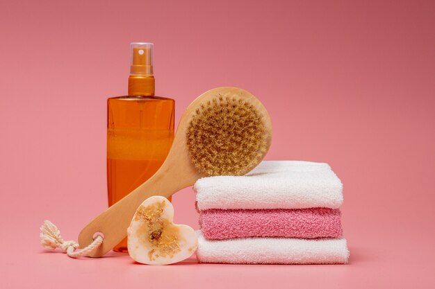 Composition à plat avec des cosmétiques spa et une serviette sur fond rose.