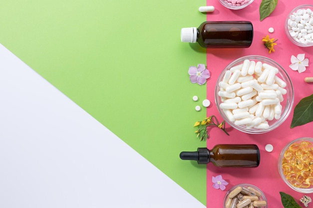 Composition à plat de diverses capsules de vitamines et de compléments alimentaires sur fond vert rose et blanc avec espace de copie Concept de denrées alimentaires