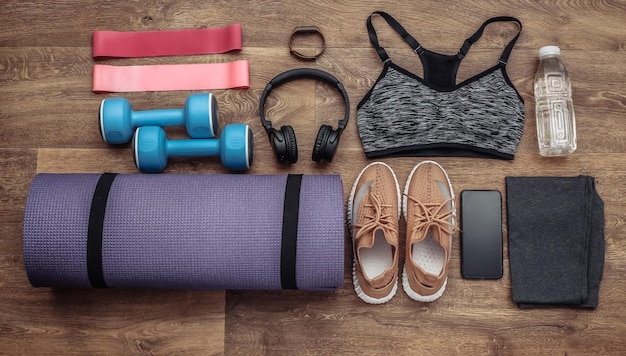 Composition à plat d'équipements sportifs, vêtements sur un plancher en bois. Concept de remise en forme, de sport et de mode de vie sain. Vue de dessus