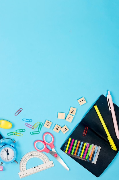 Composition à plat avec des fournitures scolaires colorées sur fond bleu