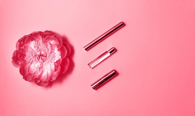 Composition à plat avec parfum de produits de maquillage décoratifs et pivoine sur fond rose