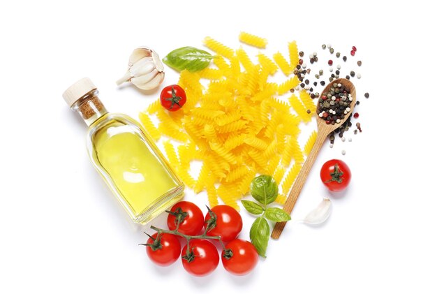 Composition à plat de pâtes de maïs, tomates cerises, épices, basilic, huile d'olive, ail isolé sur fond blanc.