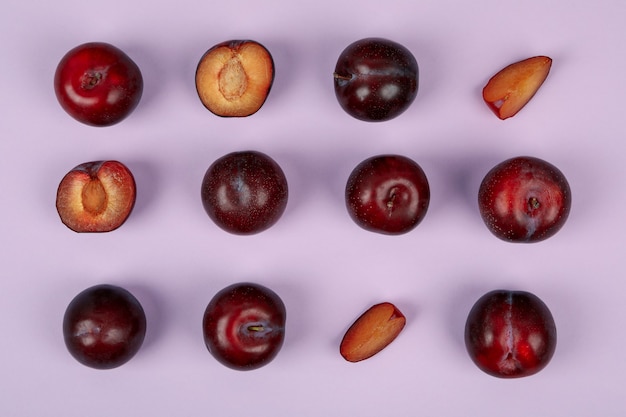 Composition à plat avec des prunes sur fond violet.