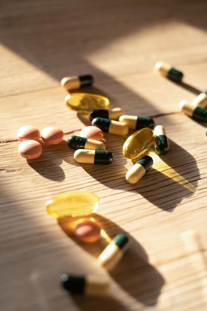 Composition à plat avec un tas de pilules colorées différentes éparpillées sur la table à partir d'une bouteille en plastique Tas de médicaments ouverts sur fond texturé de table en bois