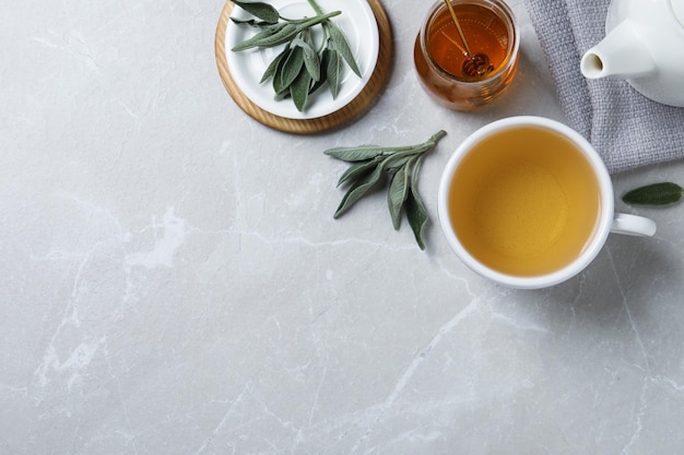 Composition plate avec du thé de sauge aromatique sur une table gris clair Espace pour le texte