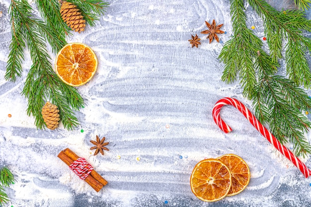 Composition plate de Noël. Cadre de branches de sapin, cônes, anis étoilé, cannelle et oranges séchées sur fond de farine.