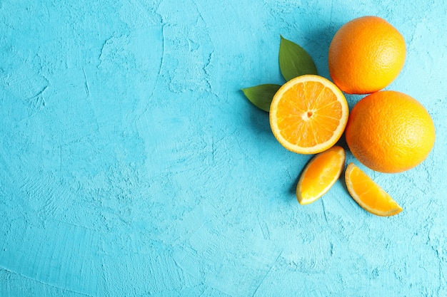 Composition plate avec des oranges mûres et des feuilles sur fond de couleur. Vue de dessus, espace pour le texte