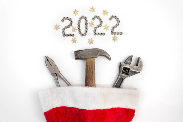 Composition plate avec des outils de construction en chapeau de père noël sur fond blanc avec lettrage 2022