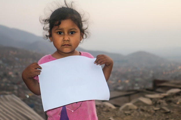 Composition pour la journée des enfants. Fille tenant une feuille de papier vierge pour insérer un texte ou un message