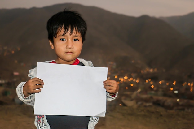 Composition pour la journée des enfants. Garçon tenant une feuille de papier vierge pour insérer un texte ou un message