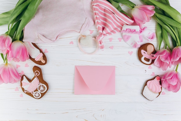 composition pour les nouveau-nés sur un fond en bois avec enveloppe, vêtements et biscuits