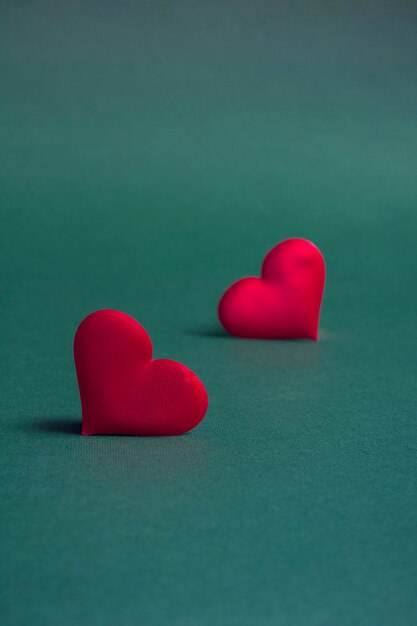 Composition pour la Saint-Valentin. Sur un fond vert, des coeurs rouges se bouchent avec un espace de copie. Format vertical