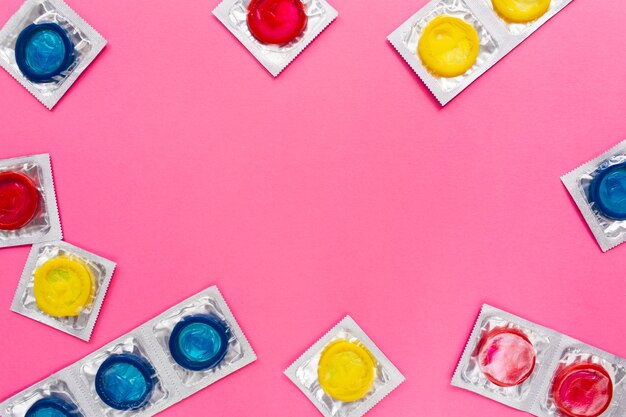 Composition avec des préservatifs colorés sur une surface rose vif
