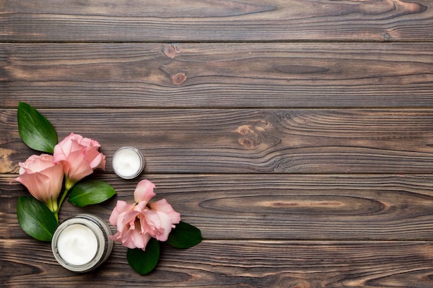 Composition avec des produits cosmétiques et de belles roses sur fond en bois. Espace de copie, mise à plat