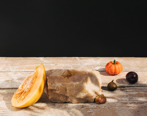 Composition rétro faite de citrouille de figues de fruits de melon et de roche sur une vieille table en bois Podium du produit.