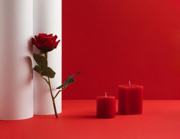 Composition romantique avec bougie et fleur rose rouge sur fond rouge et blanc idée Saint Valentin