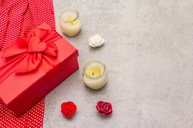 Composition de la Saint-Valentin avec boîte-cadeau rouge, tissu en pointillé, bougies et roses
