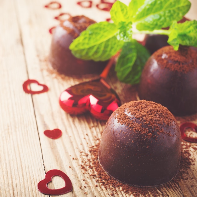 Composition de la Saint-Valentin avec des bonbons au chocolat et des coeurs sur une surface en bois vintage. Photo tonique avec espace de copie pour le texte