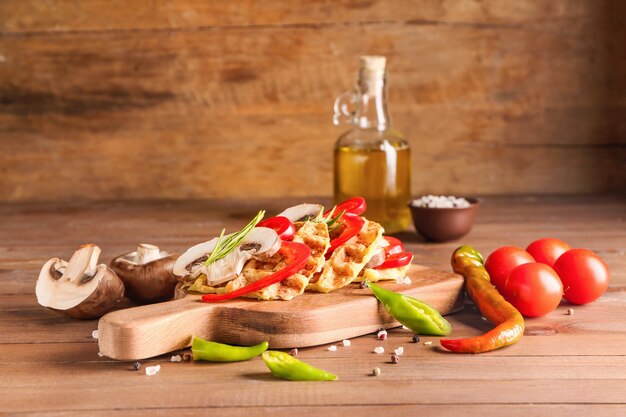 Composition avec de savoureuses gaufres à la courge et légumes sur table en bois