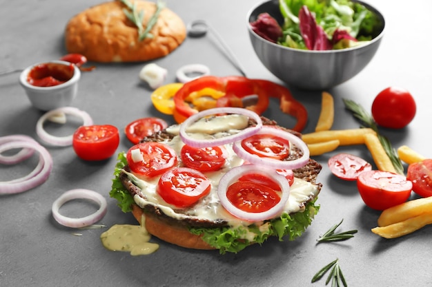 Composition avec savoureux burger et légumes sur table