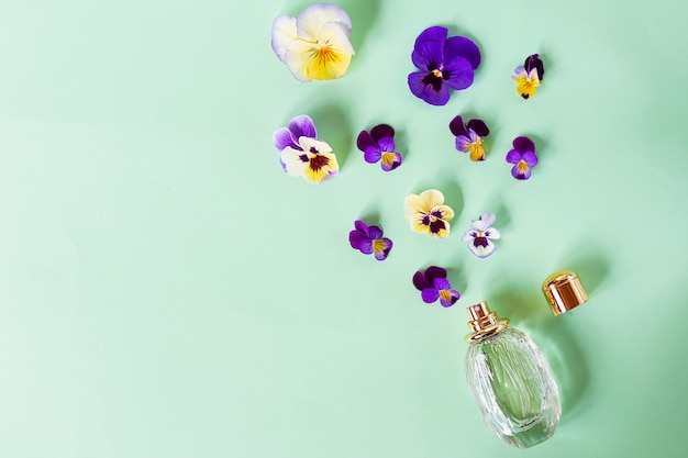 Composition, sertie de belles fleurs colorées fraîches, parfumées et vaporisateur de parfum pour femme. Violettes. Vue de dessus. Mise à plat.