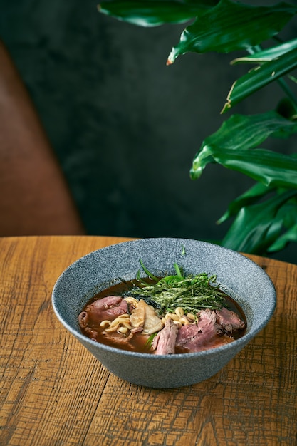 Composition avec soupe de ramen au boeuf en plaque grise sur fond de bois