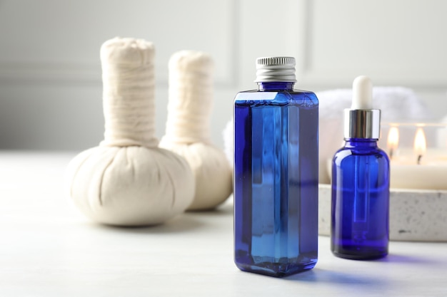 Composition de spa Bouteilles de produits cosmétiques sacs d'herbes et bougie brûlante sur table de lumière