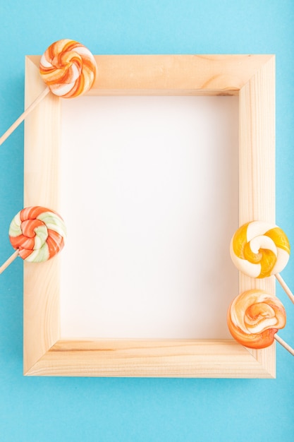 Photo composition avec sucettes et cadre en bois sur pastel bleu
