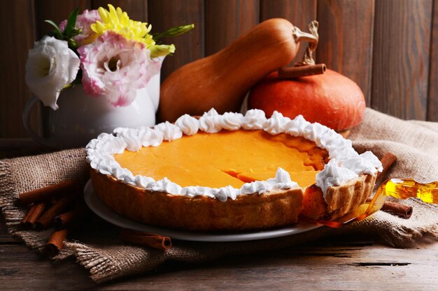 Composition de tarte à la citrouille maison sur assiette et citrouilles fraîches sur fond de bois