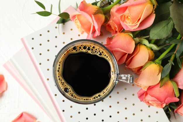 Composition avec tasse de café, cahiers et roses roses, vue de dessus