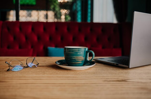 Composition une tasse de café, des verres et un ordinateur portable sur la table