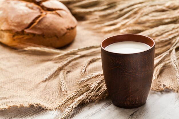 Composition avec tasse de lait, pain et épis de seigle sur sac.