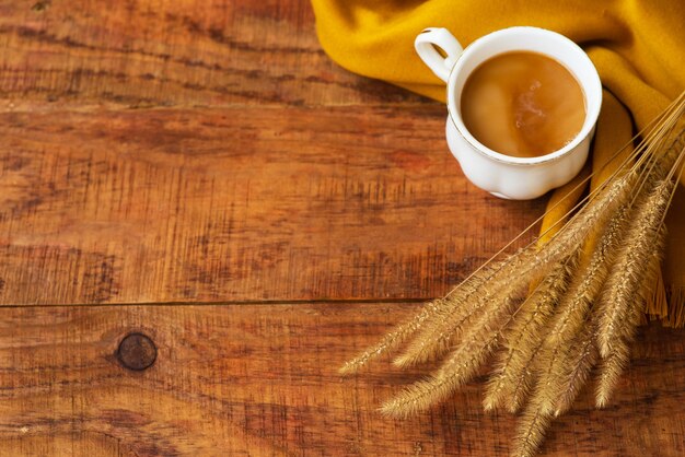 Composition de tasse de thé d'automne avec du lait, des écharpes jaunes et des épillets de blé sur un fond en bois