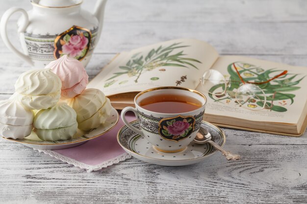 Composition de tasse de thé et livre ouvert sur une table basse dans la chambre, gros plan