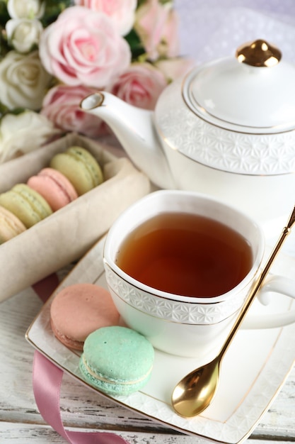 Composition avec théière macarons colorés et place de thé sur fond de bois de couleur