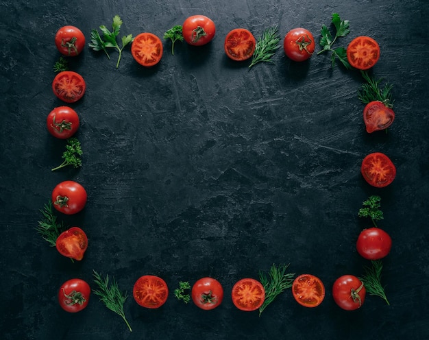 Composition de tomates rouges et de persil frais vert et d'aneth allongé sur fond sombre sous forme de cadre Concept de nourriture végétarienne Espace libre au milieu