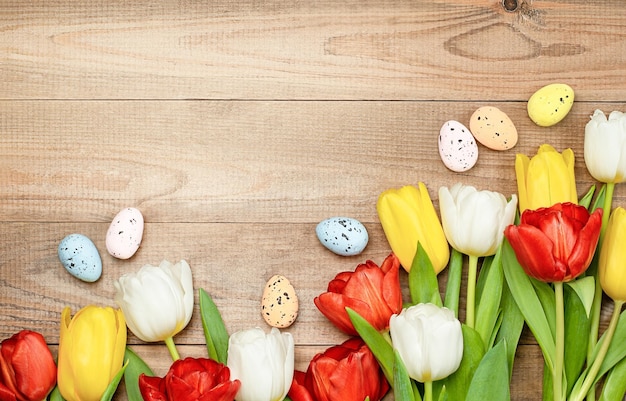 Composition de tulipes et d'oeufs de pâques sur une vue de dessus de table en bois