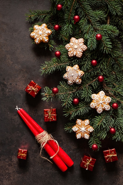 Composition de vacances de Noël avec des branches de sapin, des cônes, du pain d'épice, un décor de Noël et deux bougies rouges
