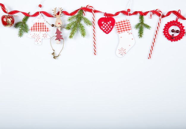 Composition de vacances de Noël. Motif rouge créatif festif, vacances de décoration à la main de Noël avec ruban, cannes de Noël, cadeau, sapin de Noël et décorations rouges sur fond blanc.