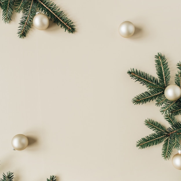 Composition de vacances de Noël nouvel an. Maquette de cadre avec espace copie vierge, branches d'aiguille de sapin, boules de Noël sur beige