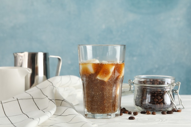 Composition avec verre de café glacé sur table en bois blanc