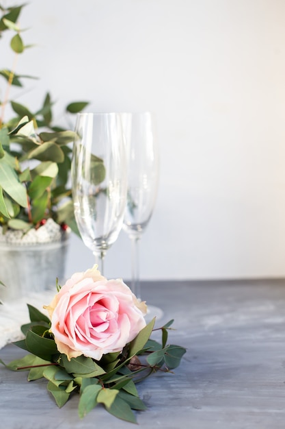 Composition avec verre à champagne. Fleurs et coeurs sur fond de béton gris.