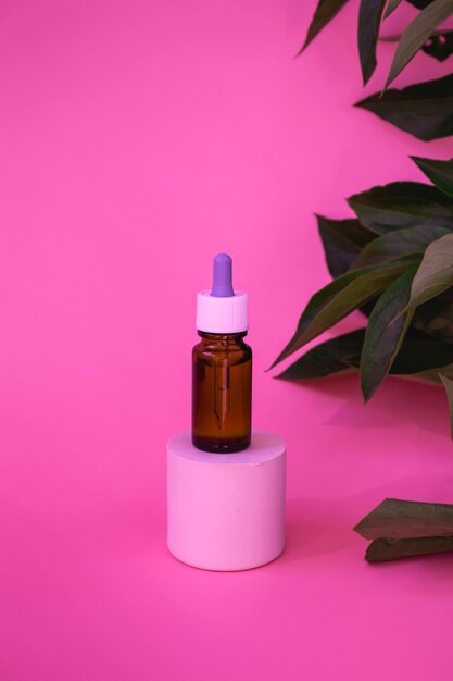 Composition En Verre Foncé Avec Des Produits Cosmétiques Et Médicaux. Bouteilles Contenant Des Médicaments Contre Les Allergies Ou Du Sérum, Des Huiles Sur Les Podiums Avec Des Feuilles De Pivoine Sur Fond Rose. Photo Verticale