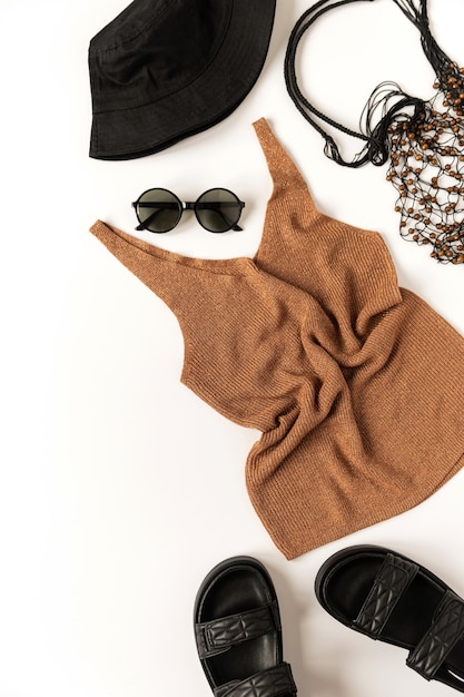 Composition de vêtements de mode esthétique d'été féminin avec chapeau panama pantoufles lunettes de soleil sac à cordes supérieur sur fond blanc Vue de dessus à plat concept de tissu minimal