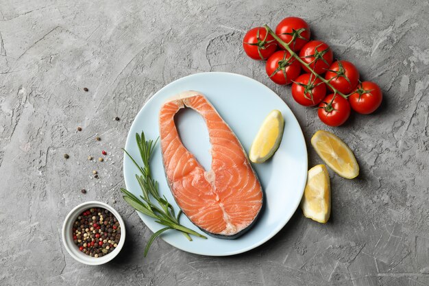 Composition avec viande de saumon et ingrédients sur table grise, vue de dessus